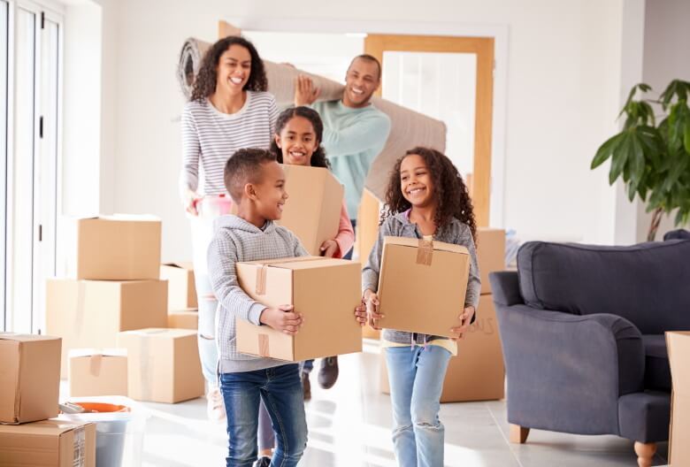 Smiling family carrying boxes into new home on moving day